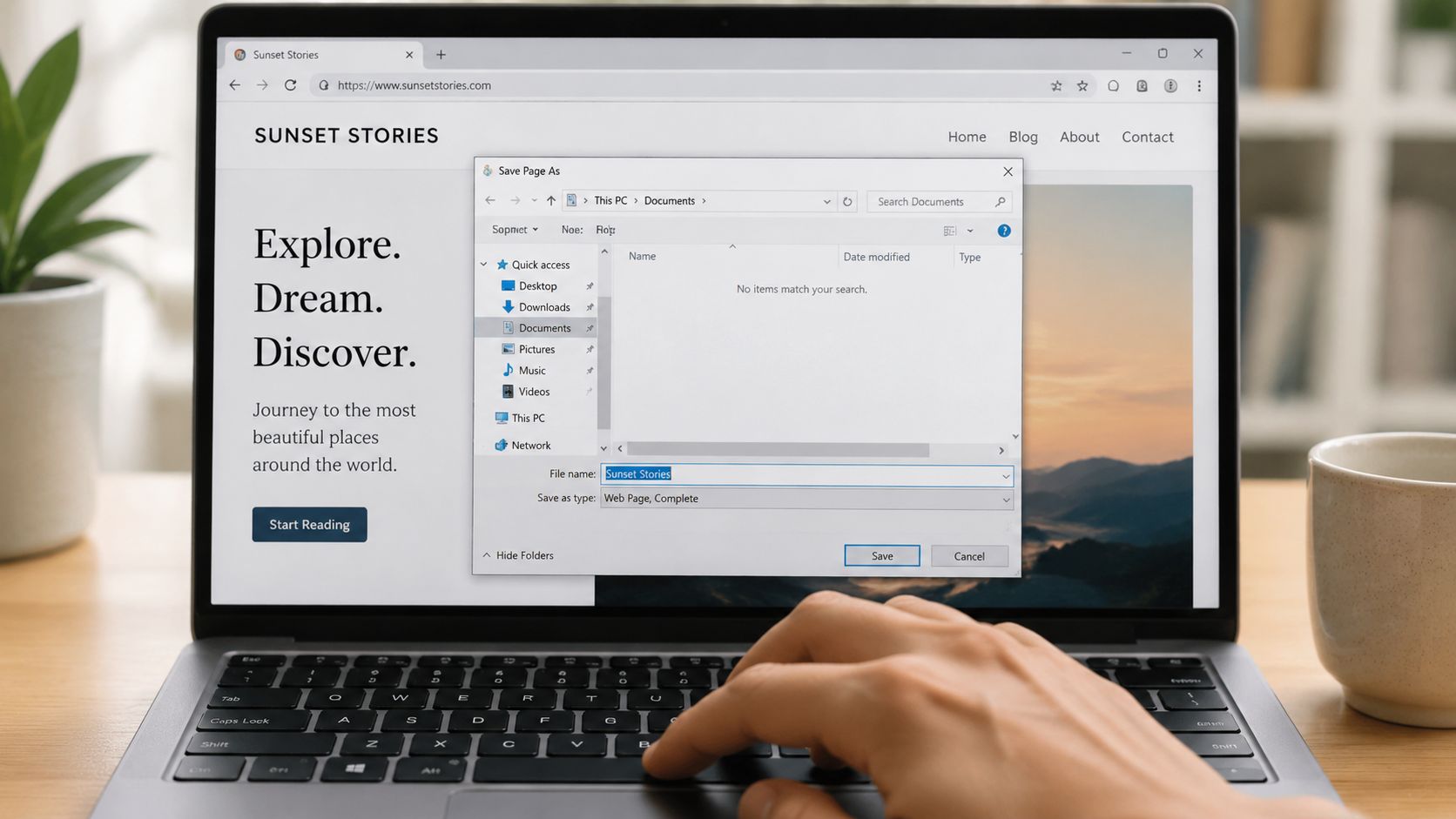 A close-up view of a person using a laptop to save a webpage file in a browser window.